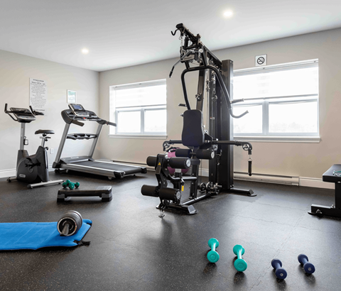 A gym with a variety of equipment including treadmills, elliptical machines, and weights.