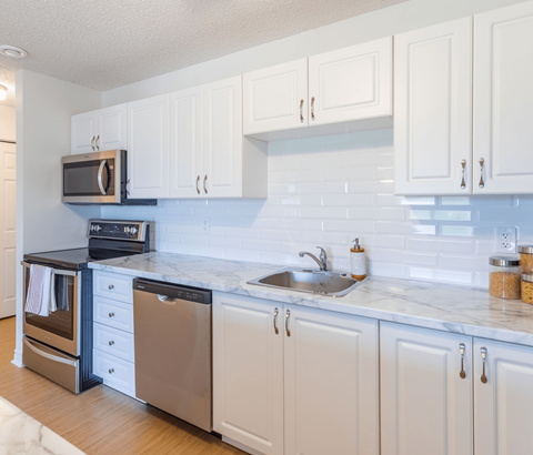 A kitchen with white cabinets and a marble countertop.