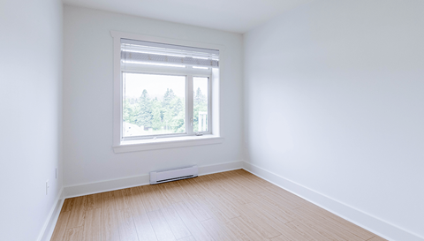 A room with a window and a radiator on the floor.