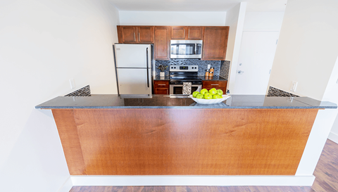 A kitchen with a wooden island and a bowl of apples on it.