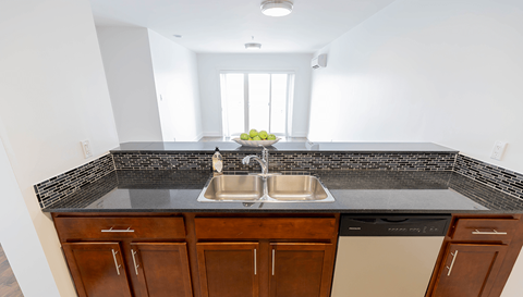 A kitchen with a black countertop and brown cabinets.