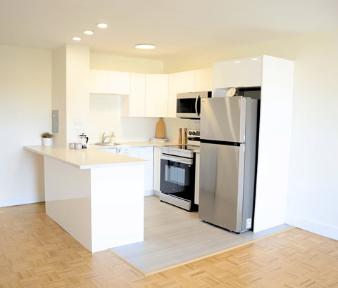 A modern kitchen with a white island and stainless steel appliances.