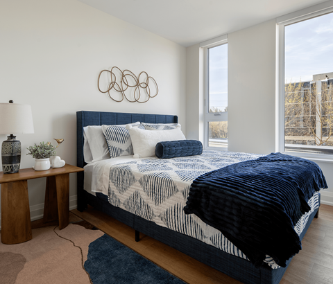 A bedroom with a large bed and a blue rug.