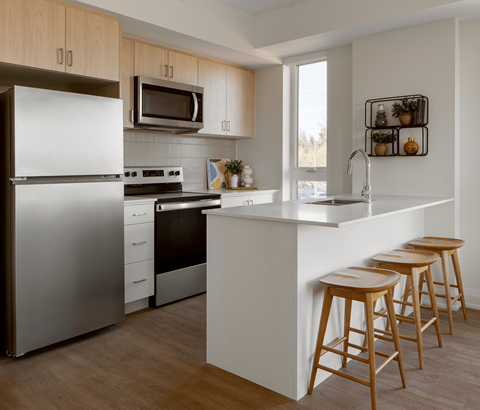 A modern kitchen with a refrigerator, stove, and bar stools.