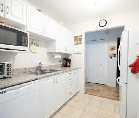 A kitchen with white cabinets and a white refrigerator.
