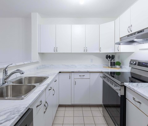 A kitchen with white cabinets and a marble countertop.
