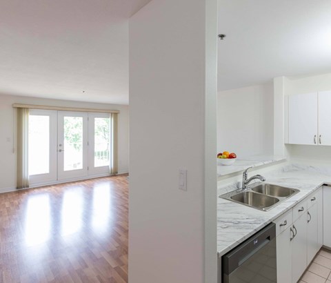 A kitchen with white cabinets and a marble countertop.