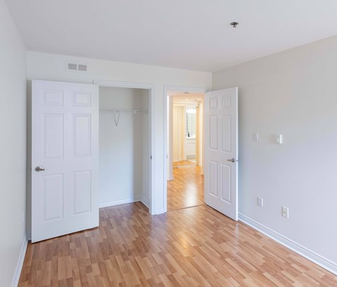 A room with white walls and wooden flooring with two white doors.