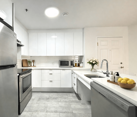 A modern kitchen with white cabinets and stainless steel appliances.
