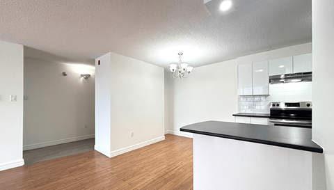 A kitchen with a black counter top and white walls.