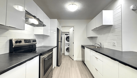 A modern kitchen with white cabinets and black countertops.