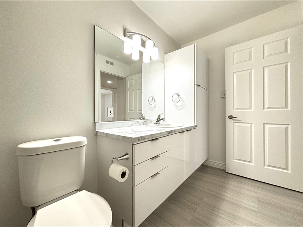 A white bathroom with a toilet, sink, and mirror.