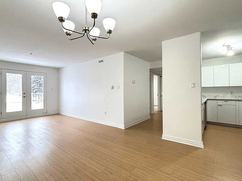 A large empty room with a chandelier and wooden floors.