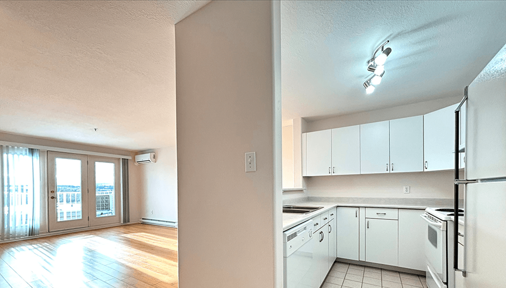 A kitchen with white appliances and wooden floors.