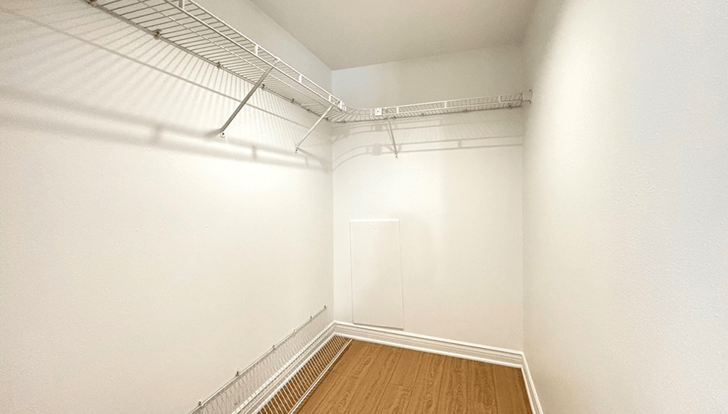 A white room with a wooden floor and a metal railing on the ceiling.
