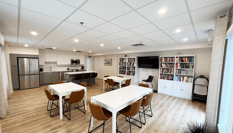 a community room with tables and chairs and a kitchen