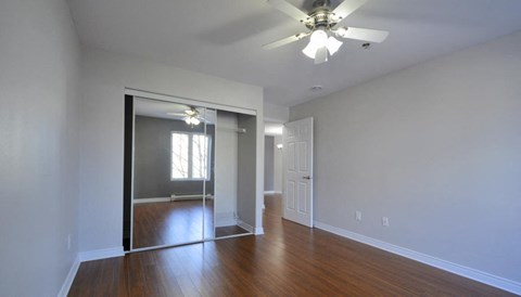 an empty living room with a ceiling fan and a closet