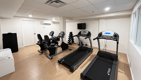 a gym with treadmills and other exercise equipment in a room with wooden floors