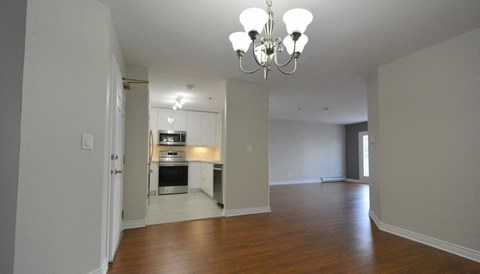 an empty living room and kitchen with a chandelier
