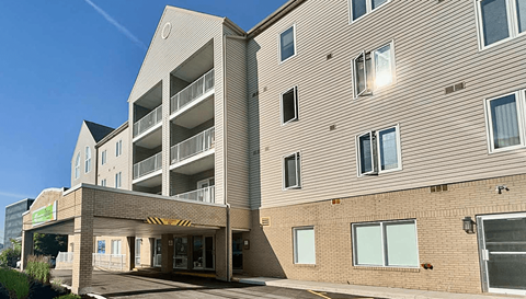 A modern building with a large entrance and a parking garage attached to it.