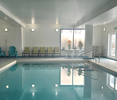 A large indoor swimming pool with a row of chairs and a staircase.