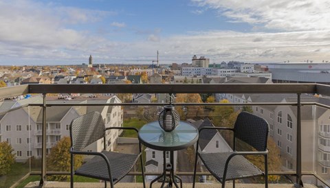 a balcony with a view of a city and a table and chairs