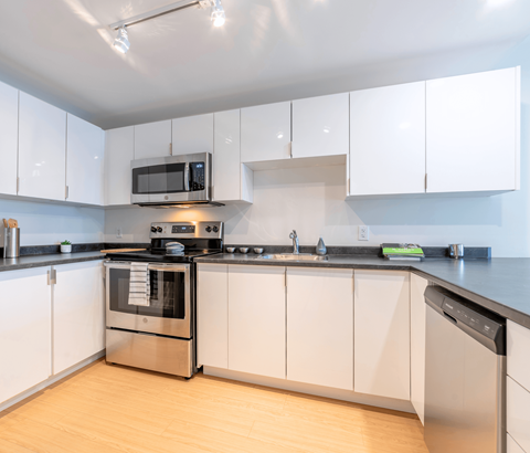 A modern kitchen with white cabinets and stainless steel appliances.