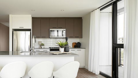 A modern kitchen with white chairs and a black door.