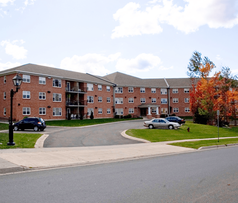 A large red brick building with a parking lot in front.