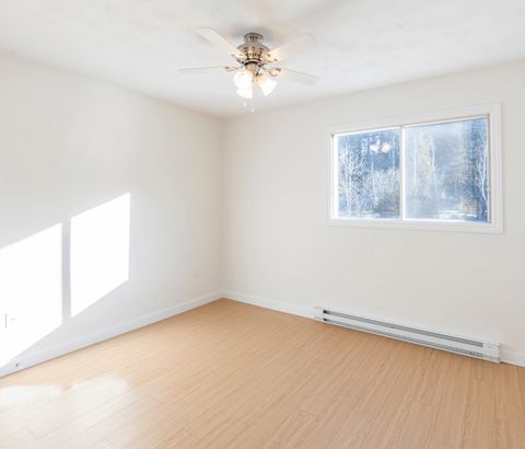 A room with a ceiling fan and a window showing a snowy scene outside.