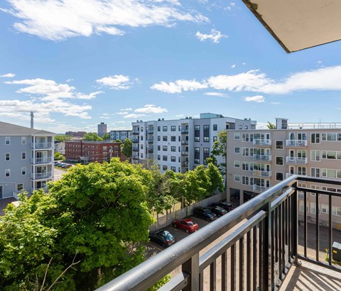 A balcony overlooks a parking lot and buildings.