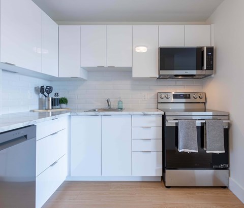 A modern kitchen with white cabinets and appliances.