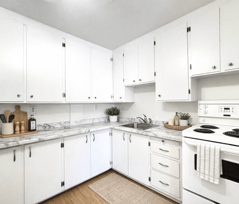 A kitchen with white cabinets and a white stove top oven.