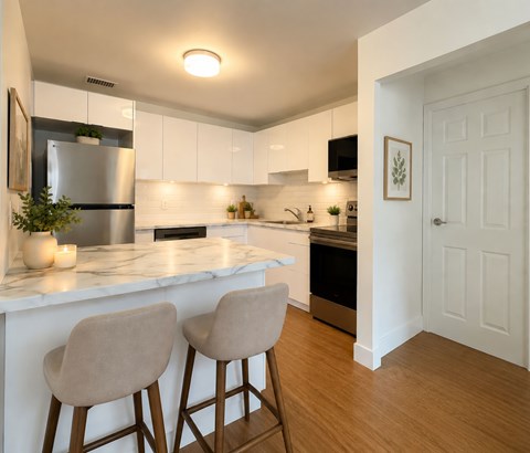 A kitchen with white cabinets and a marble countertop.