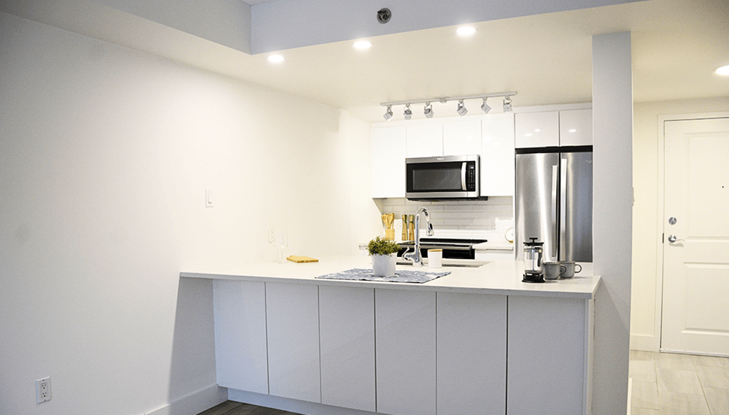 A modern kitchen with white cabinets and stainless steel appliances.