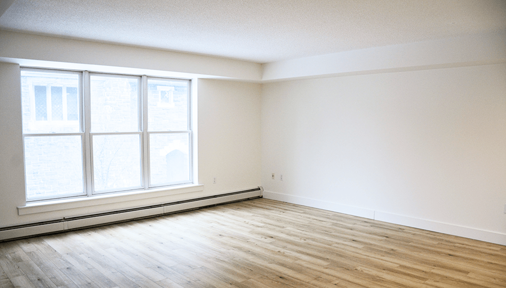 A room with a window and wooden flooring.