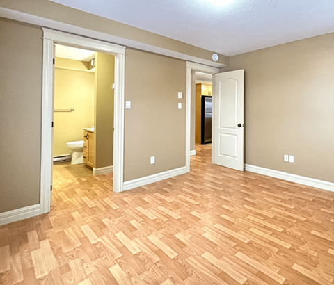 A room with wooden flooring and two doors.