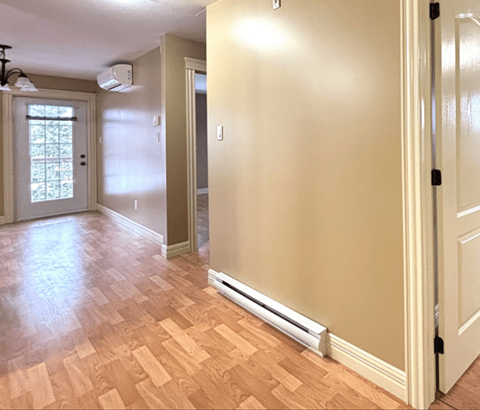 A room with a wooden floor and a wall-mounted air conditioner.