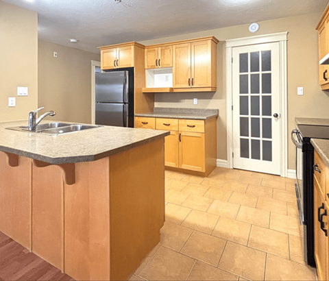 A kitchen with wooden cabinets and a black refrigerator.