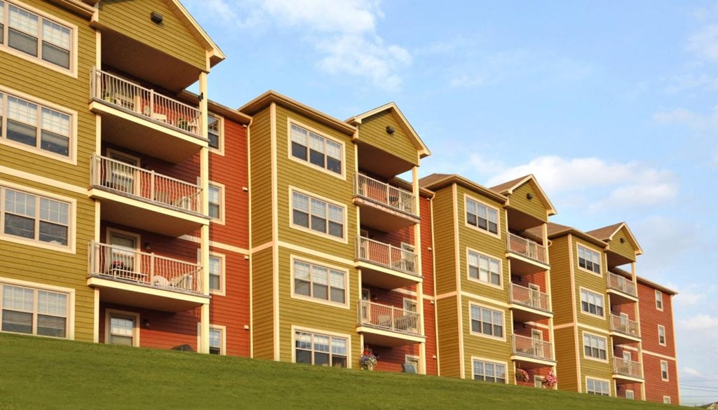 Apartment building with balconies and windows on a sunny day.