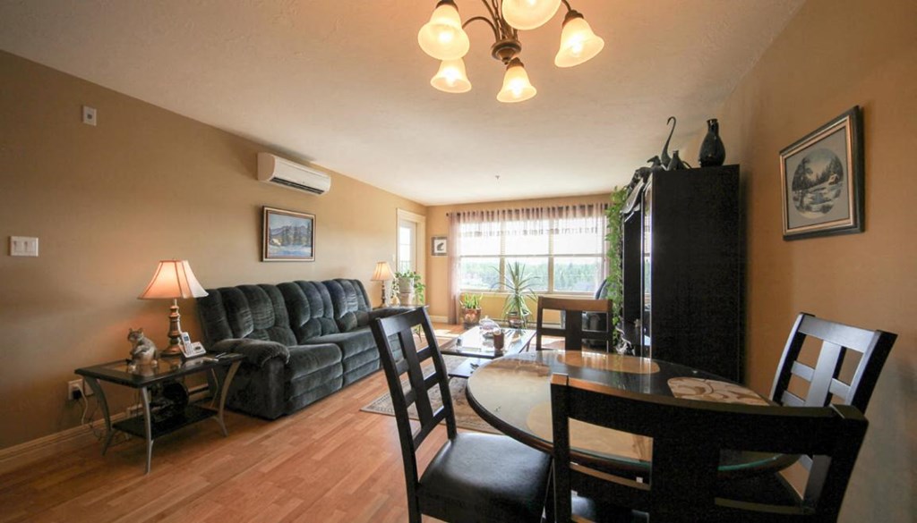A living room with a black sofa, a wooden table, and a black chair.
