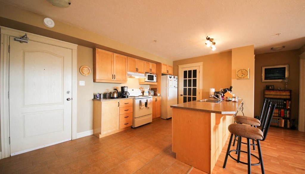 A kitchen with wooden floors and a white door.