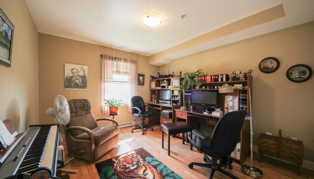 A living room with a piano, chairs, and a TV.