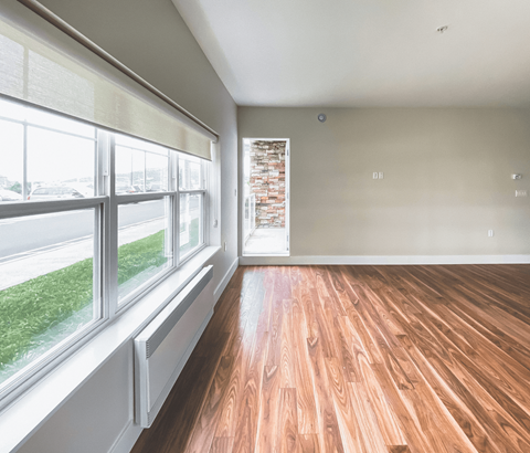 A room with wooden floors and a window overlooking a street.