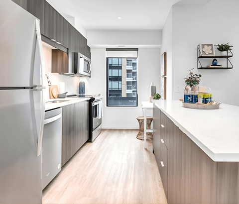 A modern kitchen with a large refrigerator and wooden flooring.