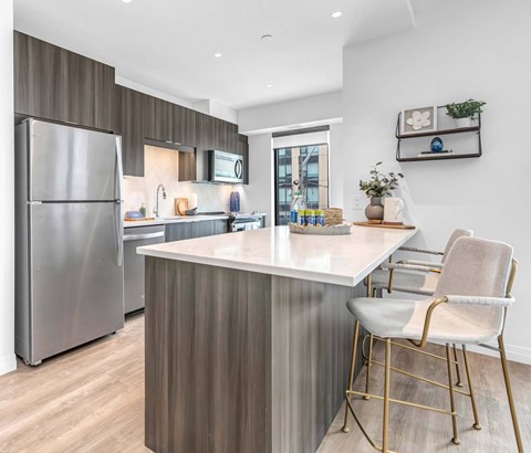 A modern kitchen with a stainless steel refrigerator and a white countertop.