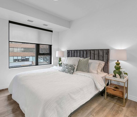 A bedroom with a large bed and a window with blinds.