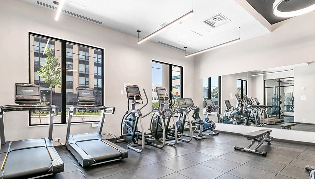 a gym with cardio equipment and windows in a building
