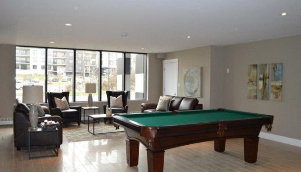 A pool table is in the middle of a room with a couch and chairs.