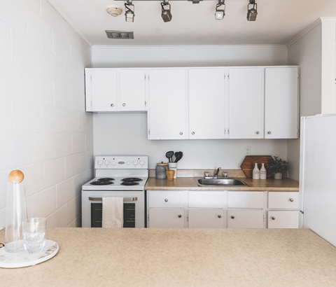 A white kitchen with a stove, sink, and cabinets.
